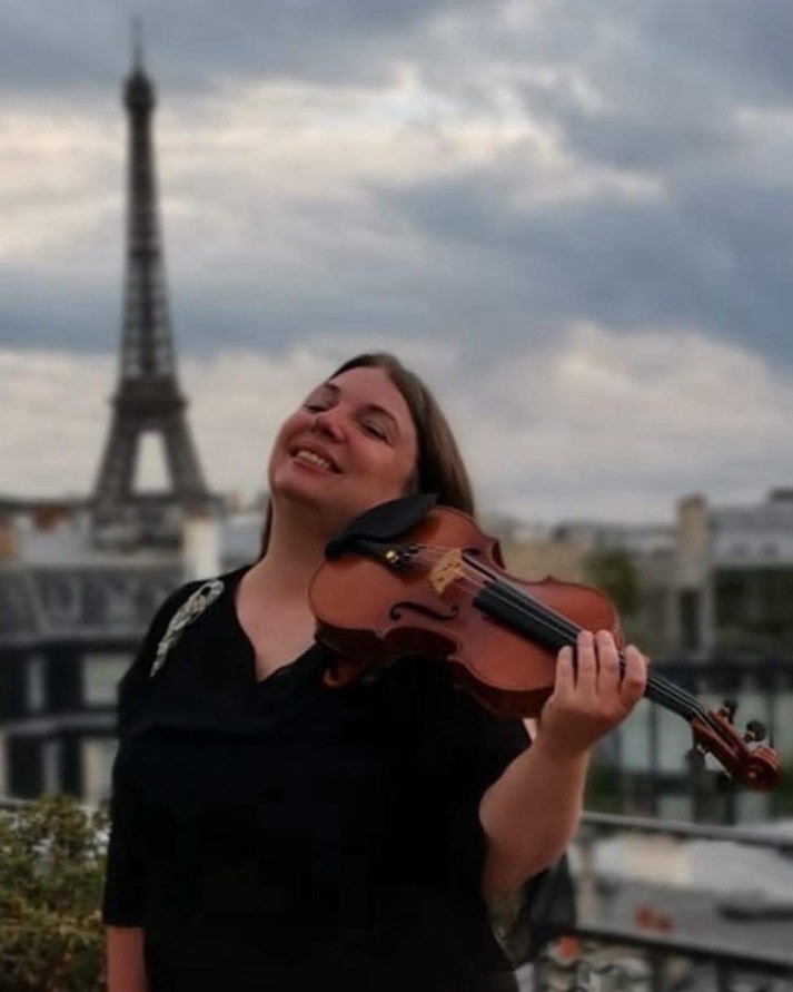 Maria Christiany, fondatrice et directrice artistique d’UNIART, violon à la main devant la Tour Eiffel